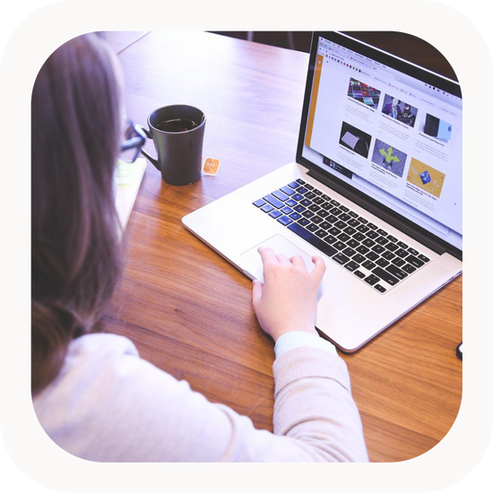 Women working on laptop at brown desk.